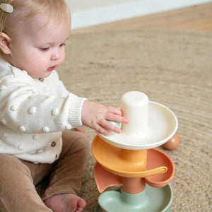 Baby is placing the running ball into the little dutch spiral tower.
