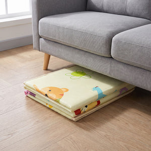 The Allis Double Sided Folding Play Mat folded compactly and tucked away neatly underneath a grey living room sofa for easy space-saving storage.