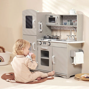 A girl is playing pretend play by sitting near the Kidoz grey kitchen.
