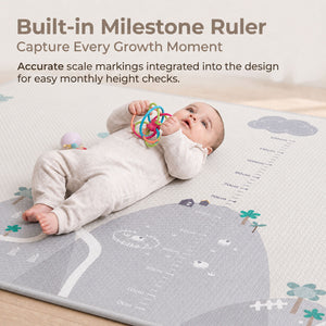 A baby lying on a large printed measurement play mat with height and weight milestone markings, holding a colorful ring toy. Text at the top reads 'Built-in Milestone Ruler' and 'Capture Every Growth Moment.
