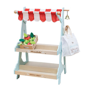 Toy farmers market stand with a red and white striped canopy, fruits, and a bag on a white background.