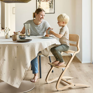 The chair adjusted for a young child, with the footrest lowered to accommodate longer legs, providing ergonomic seating for dining.