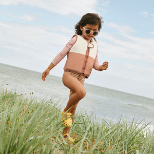 Child enjoying beach day wearing Liewood swim vest.