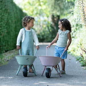 Two kids are playing with the wheelbarrow.