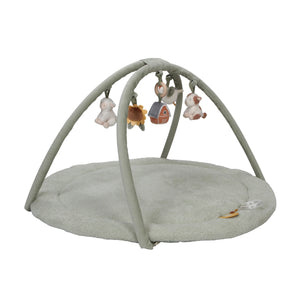 A green little dutch play mat with two corduroy arches and hanging toys shaped as a chicken, cow, sheep, flower, and barn.