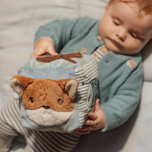 Baby playing with the soft activity cube, holding and exploring its different sensory elements.