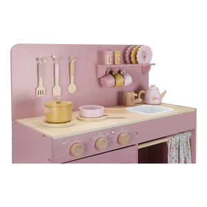 Pink toy kitchen with plates, cups, and utensils.