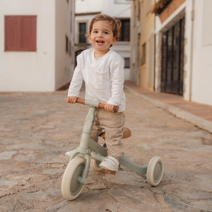 Child holding natural wood finish Little Dutch tricycle ready to ride