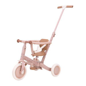 Side profile of the Little Dutch 4-in-1 Tricycle in soft pink, configured as a push tricycle featuring an adjustable parent steering bar, safety ring, and secure harness.