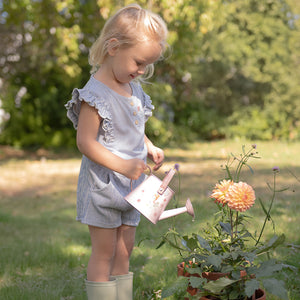 A girl watering a plant with the Little Dutch watering can.