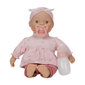 Little Dutch Baby Lily doll sitting on a white background, wearing a pink floral top, maroon pants, and a headband, with a pink pacifier in its mouth and a milk bottle beside it.