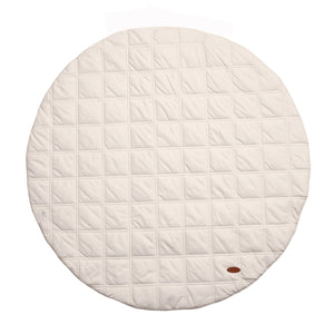 A round, cream-colored baby play mat made from organic cotton with a quilted pattern.