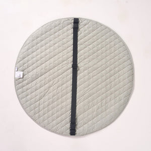 Solid light green reverse side of the playmat laid flat, featuring a black fabric strap running across the center.