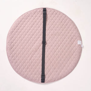 Solid pink reverse side of the playmat laid flat, showing a black fabric strap running across the center.