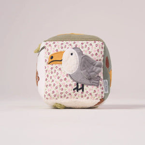 Side panel of the MiniDream jungle activity cube displaying a colorful plush toucan to stimulate newborn visual tracking.