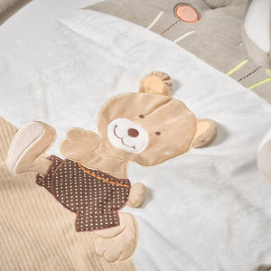 Plush teddy bear toy with a brown sweater on a white blanket