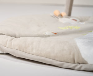Close-up of a beige textured blanket with embroidered designs on a light background