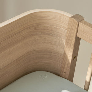 Oak-colored cot bed with smooth finish and clean lines