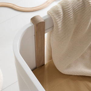 Compact baby cot with rounded edges and smooth wooden finish