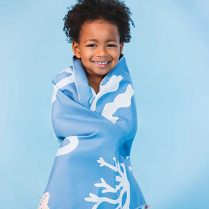 A kids is draped in a beach towel and smiling.