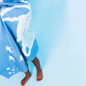 A kids is draped in a swim essentials beach towel.