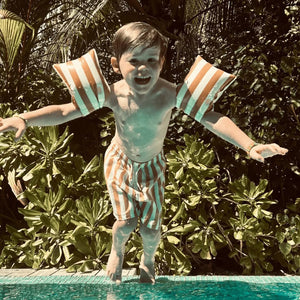 A kids is enjoying summer in the pool.