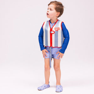 A boy is standing wearing the swim essentials swim vest in red and blue colour.