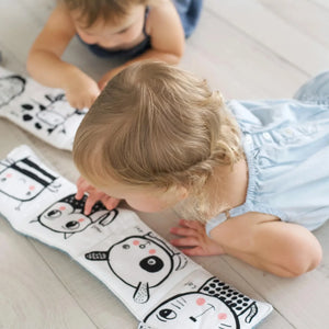 Baby exploring sensory pages of Wee Gallery cloth book.