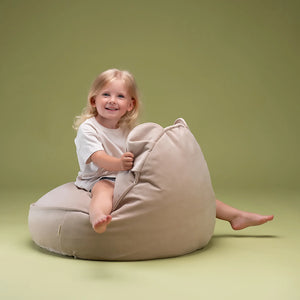 A girl is sitting on the bean bag chair and smiling.