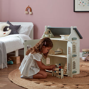 A child is playing with an 11-piece wooden dolls house furniture set.