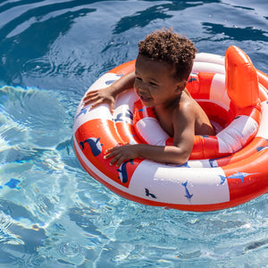 A smiling baby enjoying the water in a Swim Essentials Whale Baby Float.