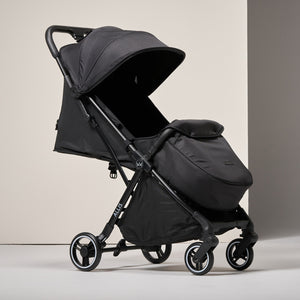Black stroller with footmuff on a light grey background