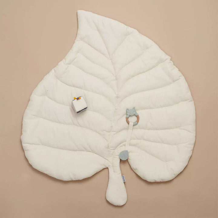 White leaf-shaped baby playmat with sensory toys.