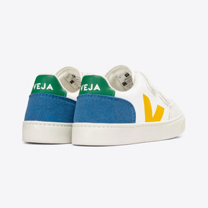 White Veja kids' sneakers on a wooden floor, minimalist style