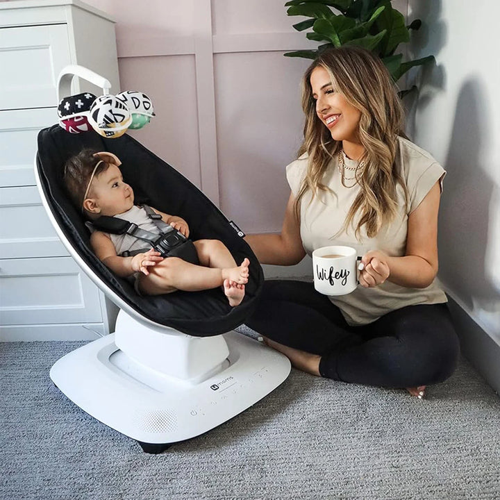 Image of a baby smiling and playing with the mamaRoo®5 mobile.
