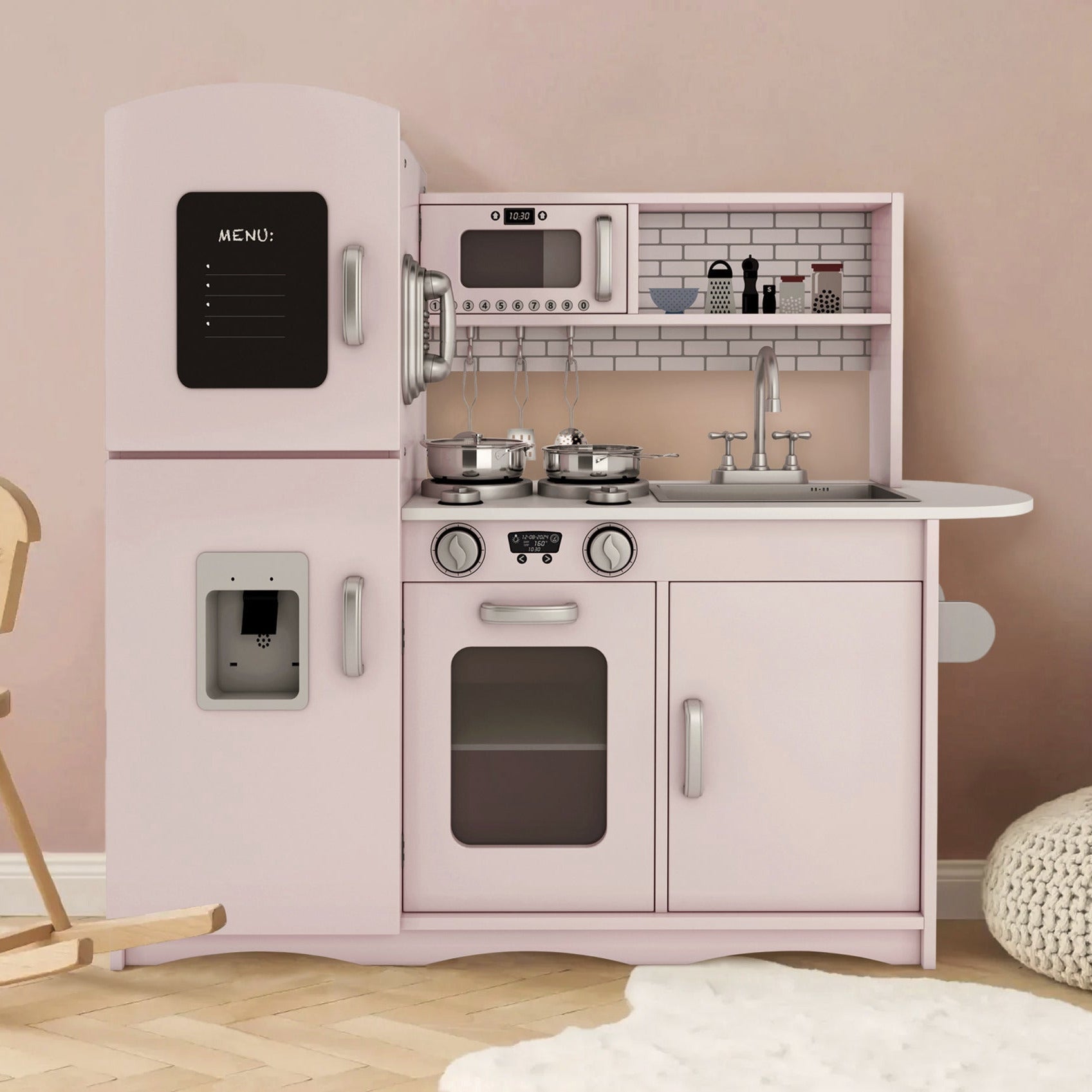 Children's play kitchen set with pink refrigerator, stove, and sink against a beige wall.
