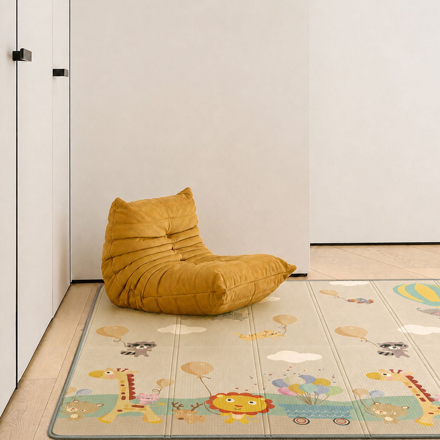 A mustard yellow crescent-shaped bean bag chair sits on a light beige children's play mat with cartoon animals and clouds, placed in a minimalist room corner with white walls and light wood flooring.