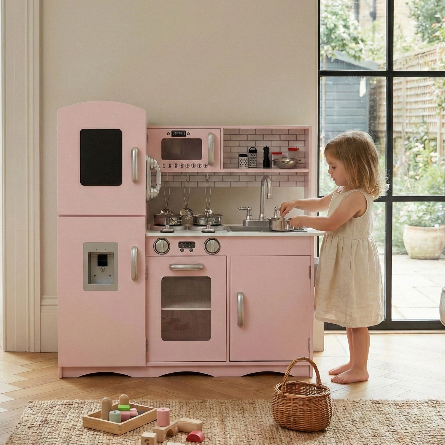 A girl is playing with the pink play kitchen