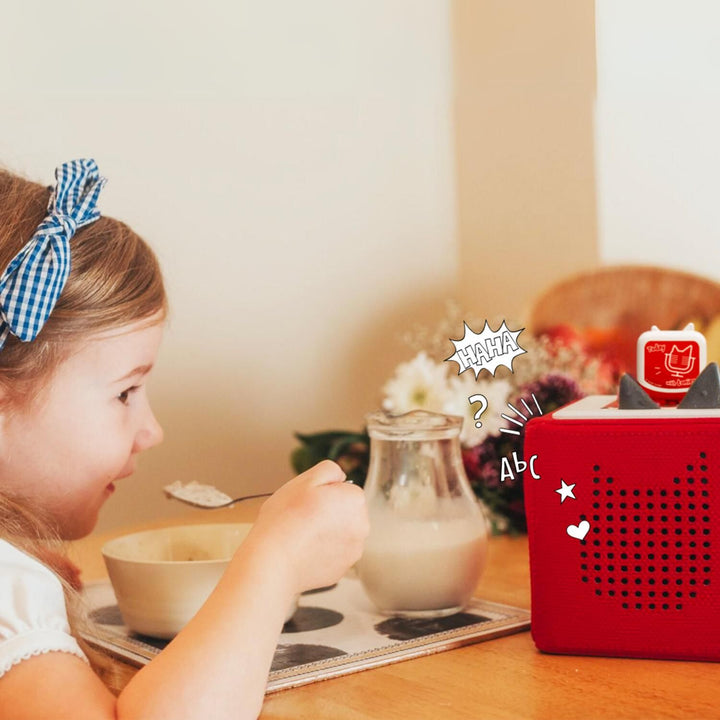 A child enjoys breakfast while listening to an engaging podcast tonie on their Toniebox.