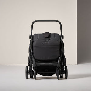 Folded black flick stroller on a light grey background