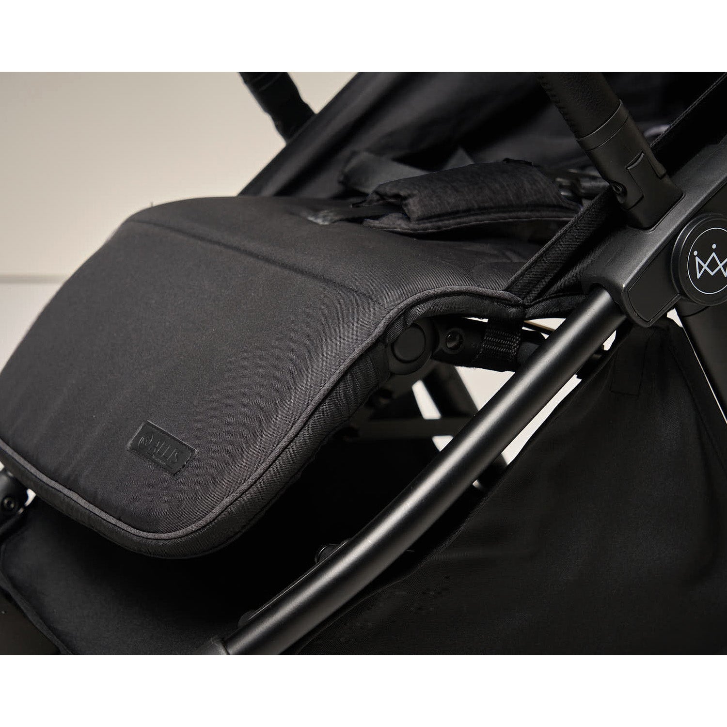 Black stroller accessory attached to a stroller with a neutral background