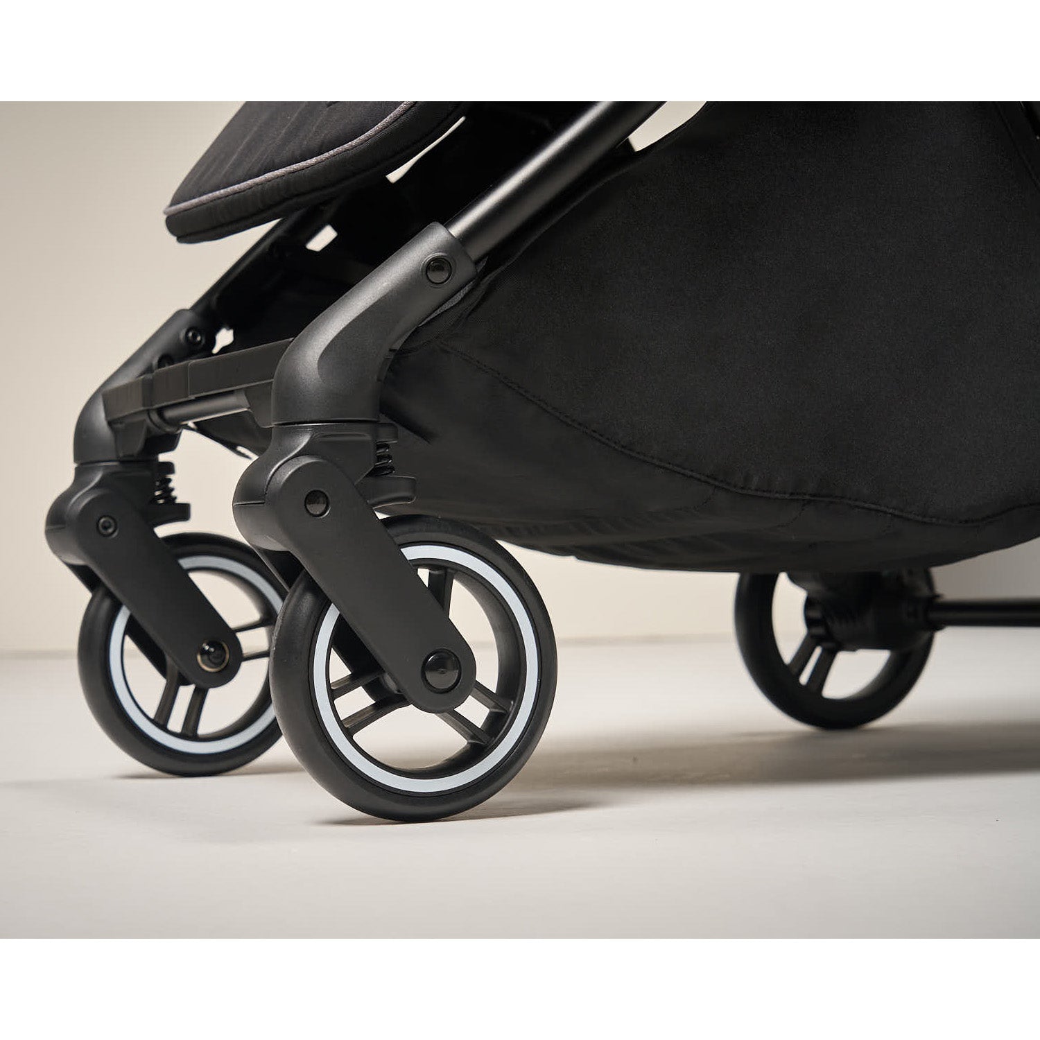 Close-up of a black stroller with 360° wheels on a light background