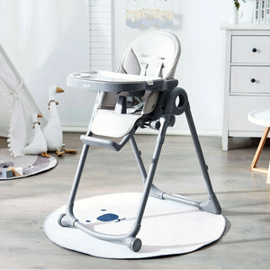Allis baby high chair with a white tray and seat, and a grey frame. The high chair is sitting on a light-colored rug in a child's room. There are stuffed animals and toys scattered around the rug.