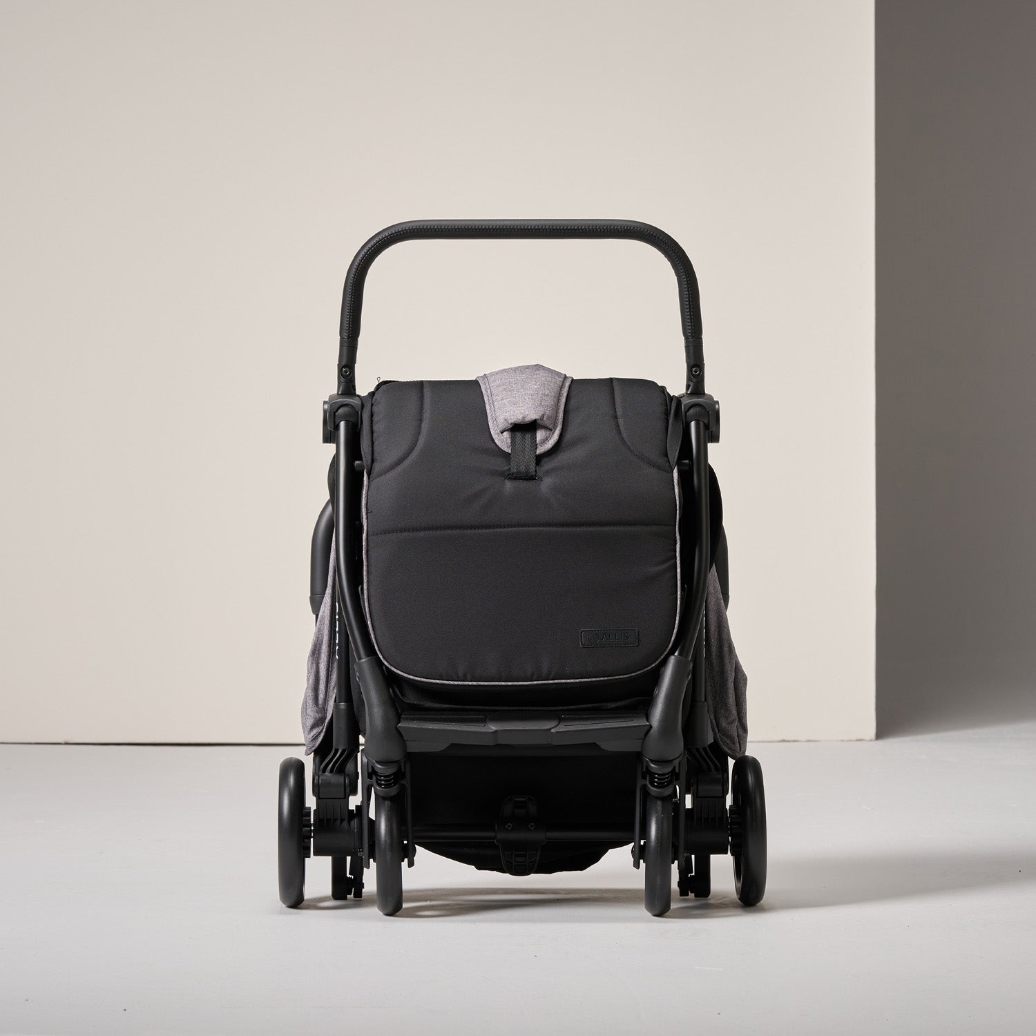 Folded black and grey stroller on a light grey background