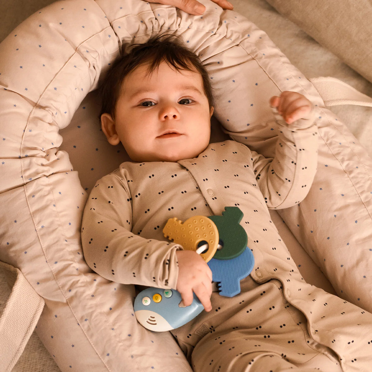 Baby happily holding and exploring Liewood VROOM car keys toy