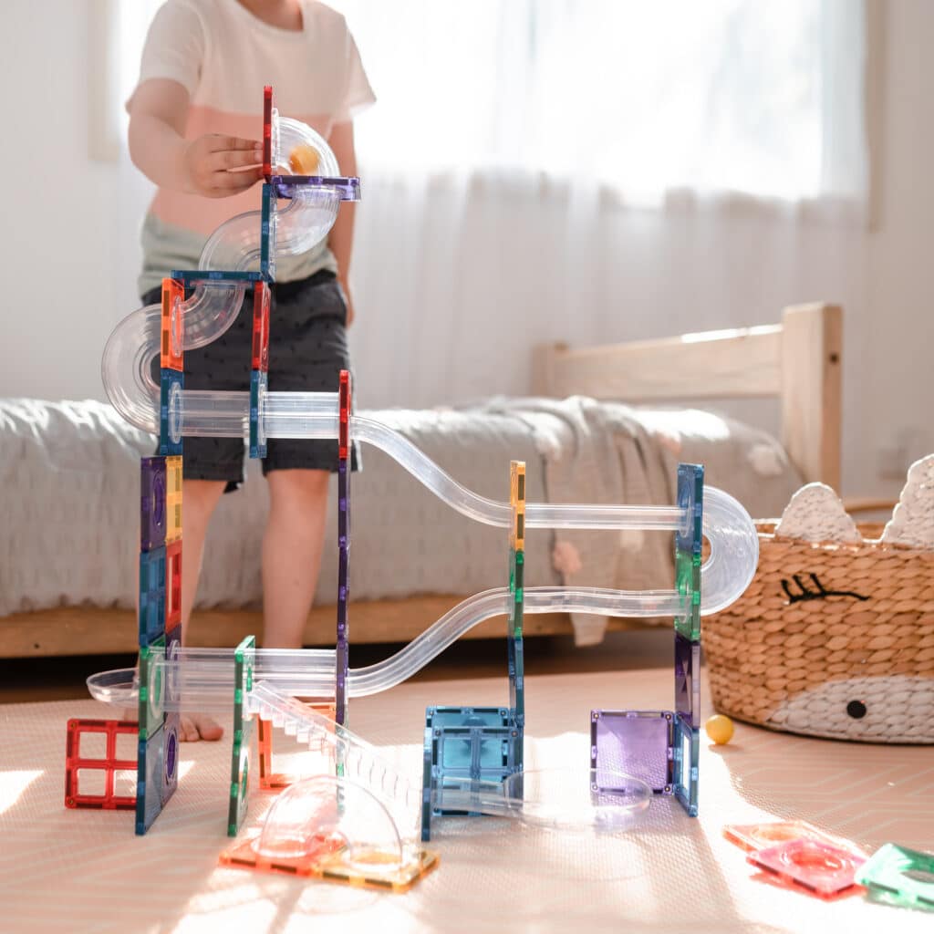 Children building a rainbow ball run with Connetix pieces