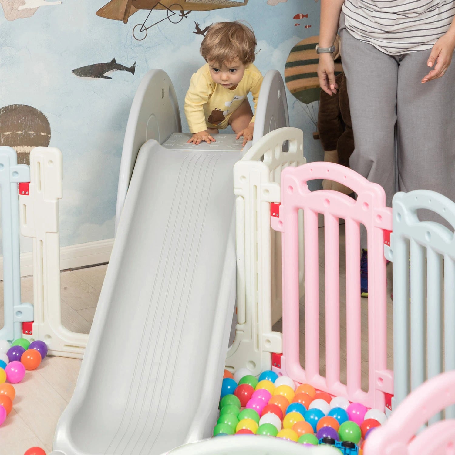 A happy toddler sliding down the elephant slide with a big smile.
