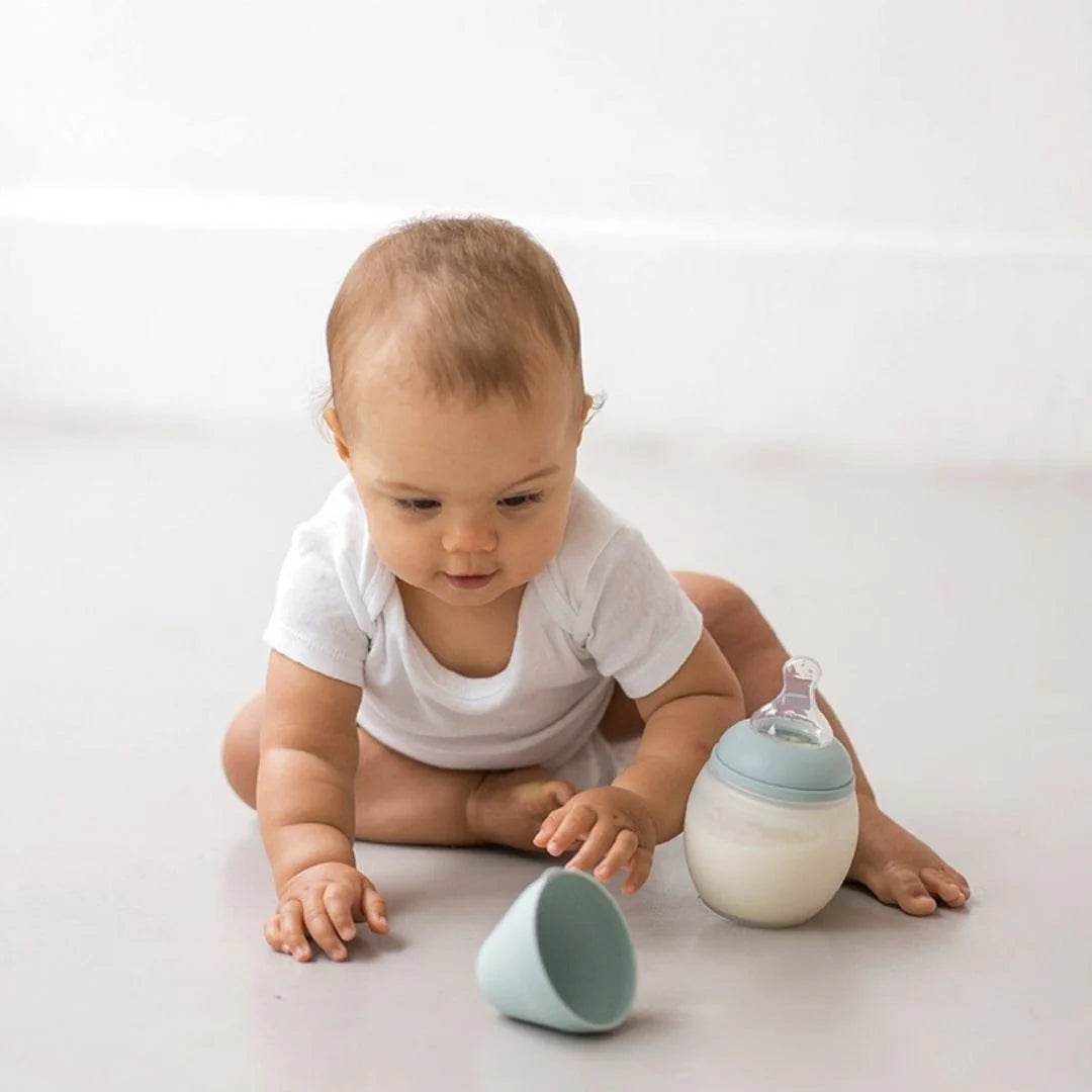 A baby is playing and drinking with the Elhee baby bottle.