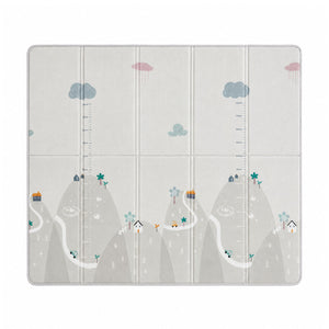 A tablet case with a playful children's landscape print, featuring stylized mountains, winding roads, small houses, trees, and clouds on a light gray background. The case is designed with built-in measurement scales on the left and right sides.
