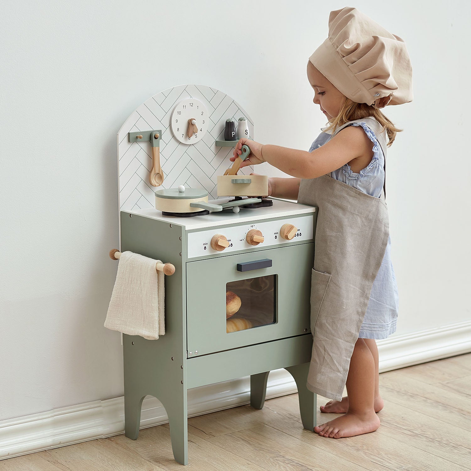 Child playing with a mint kitchen set in a room with a white wall.